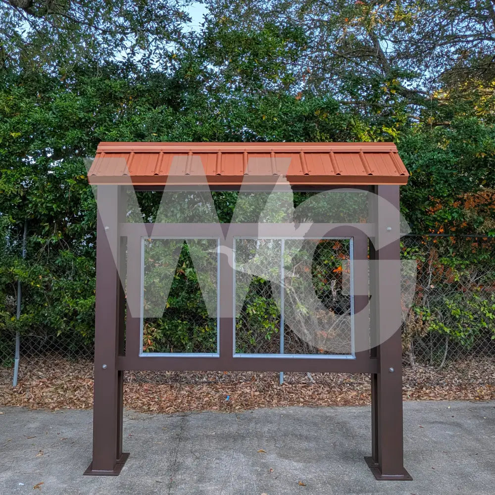 Outdoor information kiosk with a brown roof and frame, surrounded by greenery.